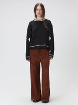 Sweater de punto con diseño de ochos en color verde, cuello redondo con detalle de franja en contraste, y apliques de rombos en las mangas. Presenta un bordado con la letra M en el pecho.