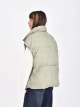 Chaleco puffer color verde oliva, con cuello alto y cierre frontal de broches a presión.