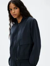 Campera tipo bomber color azul, con cierre frontal, cuello redondo acanalado, bolsillos frontales con solapa y cintura y puños elásticos.