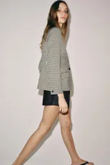Blazer de corte estructurado con estampado de cuadros vichy en tonos neutros. Presenta cuello mao en color beige, cierre frontal con botones oscuros y bolsillos con solapa en el delantero.