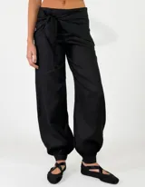 Pantalón de lino color rojo, de corte holgado con botamangas elastizadas y diseño cruzado en la cintura con lazo ajustable.