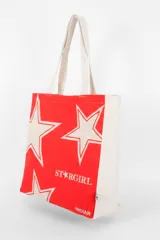 Bolso tote de tela con estampado de rayas verticales rosadas y blancas, laterales y asas en color beige. Presenta la palabra "BONJOUR" en verde en el centro y "INDIAN" en la parte inferior.