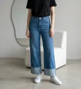 Pantalón jean de tiro alto en color azul medio, con corte recto y botamangas anchas con doblez. Cuenta con cierre frontal y bolsillos laterales.