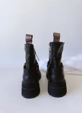 Bota corta negra de cuero, con caña media, hebilla lateral y suela track.