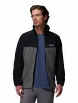 Campera polar de Columbia con cierre frontal completo, cuello alto y diseño de bloques de color en negro y gris. Cuenta con bolsillos laterales con cierre y logo de la marca bordado en el pecho.