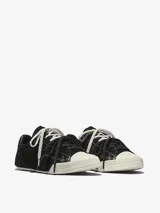 Championes Converse Chuck Taylor Low Top de ante premium color negro, con puntera de goma blanca, detalles de costuras visibles y cordones intercambiables.