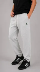 Pantalón tipo jogger de algodón color gris melange, con cintura elástica ajustable mediante cordón y puños elásticos en los tobillos. Presenta un pequeño bordado de un pájaro en color verde oscuro en la parte superior del muslo.