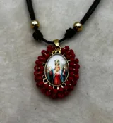 Collar ajustable con cordón azul y dije central ovalado con imagen religiosa, rodeado por una estructura de cuentas multicolores.