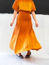 Falda larga color ocre con teñido degradado horizontal en tonos anaranjados. Confeccionada en algodón tipo seda, corte a la cintura, bolsillos laterales y cierre invisible.