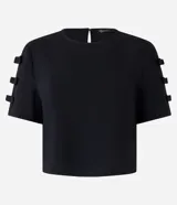 Blusa de crepé color negro, con cuello redondo, cierre tipo gota en la espalda y mangas cortas decoradas con apliques de lazos laterales.