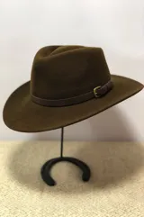 Sombrero de ala ancha confeccionado en lana impermeable, color verde oliva, con detalle de cinta de cuero marrón y hebilla metálica lateral.