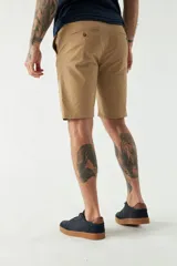 Bermuda tipo chino de gabardina con cierre de cremallera y botón, bolsillos laterales y traseros, y pasacintos en la cintura.