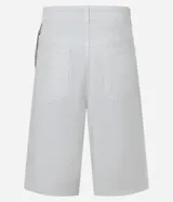 Bermuda ancha tipo baggy de sarga de algodón, color blanco, con cierre tradicional, bolsillos y detalle de cadena metálica colgante.