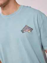 Remera holgada de algodón color beige, de manga corta y cuello redondo, con un gran estampado colorido en la espalda con diseño de olas y la inscripción 'Rusty Tribe'.