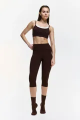 Top deportivo en tejido funcional de color marrón con tirantes dobles en color crudo y diseño de superposición. Cuenta con escote redondo y copas con relleno extraíble.
