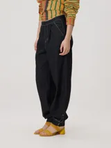 Pantalón tipo bombacha de campo color beige, de corte holgado con pinzas en la cintura y puños ajustados en los tobillos. Presenta costuras a contratono y bolsillos laterales.
