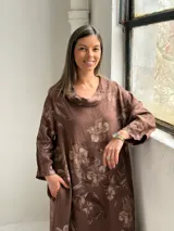Vestido largo marrón de lino con estampado floral, cuello redondo holgado y mangas tres cuartos.