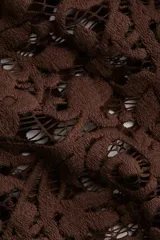 Pollera ajustada color marrón oscuro, confeccionada en encaje floral con bajo festoneado. Es de tiro alto y tiene un forro corto interior.