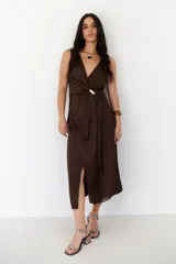 Vestido midi marrón con escote en V, sin mangas y detalle de nudo con aro dorado en la cintura.