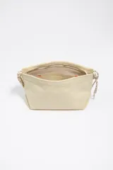Bolso de hombro mediano de piel color beige, con cierre de cremallera, asas de cordón ajustable y logo grabado en el frente.