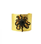 Brazalete ancho de bronce martelé color dorado con aplique central de un pulpo negro hecho con pequeñas piedras de zirconia. Es ajustable.