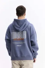 Canguro con capucha de calce oversize, color azul grisáceo. Presenta un estampado gráfico en la espalda con la inscripción 'UNDERRATED vision' y el logo de la marca Mistral. Confeccionado en tejido de algodón y poliéster.
