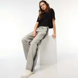 Pantalón de jean gris con lavado ácido y corte holgado. Presenta una franja vertical negra a lo largo de la pierna.