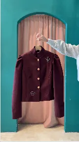 Chaqueta de paño color bordó, con cuello mao, hombros abullonados, cierre frontal con botones claros y detalles de bordados plateados.