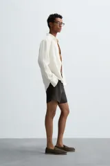 Bermuda de corte relajado confeccionada en tejido de lino color gris oscuro. Presenta cintura elástica con cordón de ajuste interno, bolsillos laterales y bolsillos traseros de plastrón.