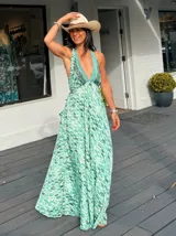 Vestido largo con estampado de hojas en tonos verde y blanco, con escote halter y espalda descubierta.