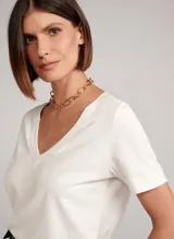 Remera blanca de tejido de punto con escote en pico y mangas cortas.