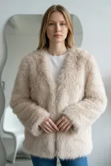 Abrigo de piel sintética en color beige, con diseño de corte recto, sin cuello y mangas largas.