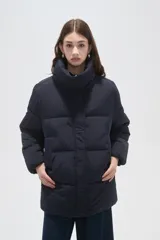 Campera puffer negra de corte holgado, con cuello alto, cierre frontal oculto y bolsillos laterales.