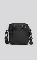 Mini bolso negro de estilo modular, confeccionado en tejido tracker impermeable. Presenta tres compartimentos con cierre y correa ajustable para llevar al hombro o cruzado.