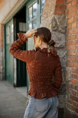 Blusa de muselina de algodón color beige, con diseño totalmente fruncido, cuello alto, mangas largas y terminaciones con volados en cuello, puños y ruedo.