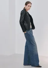 Jeans de denim azul de corte wide leg, con aplicación de pequeños tachas o strass plateados en toda la prenda.