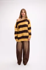 Buzo de tejido de punto con diseño de rayas horizontales anchas en color amarillo y marrón. Presenta cuello redondo, corte holgado y detalle de aberturas en los hombros.