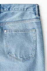 Jean de cinco bolsillos en denim de algodón rígido, con cintura estándar, cierre y botón. Corte relajado y piernas levemente acampanadas con efecto desgastado en los muslos.