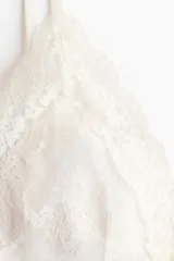 Soutien de encaje color blanco con copas triangulares, relleno extraíble y breteles finos ajustables.