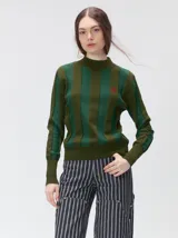 Sweater de punto con diseño de rayas verticales en tonos negro y gris oscuro. Presenta cuello alto tipo polera, mangas largas con puños ajustados y ruedo elástico. Incluye un pequeño bordado en color rojo en el pecho.