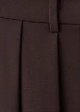 Pantalón de tiro medio color marrón, con diseño wide leg, pinzas en la parte delantera, bolsillos laterales y cierre frontal con botón, gancho y cremallera.