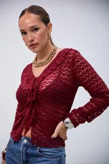 Blusa de encaje color bordó, de manga larga, con escote en V y volados en el borde delantero.