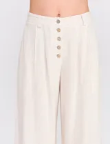 Pantalón palazzo color blanco, confeccionado en mezcla de lino y viscosa, de tiro alto con cierre frontal de botones, pinzas en la cintura y piernas anchas.