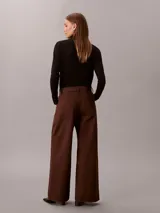 Pantalón chino de pierna súper ancha color marrón, tiro alto, con diseño de cinco bolsillos, cierre de botón y cremallera, y detalles distintivos de la marca Calvin Klein.