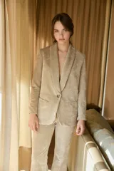 Blazer de terciopelo color beige, con solapas tipo chal, cierre frontal de un botón y bolsillos laterales con solapa.