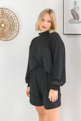 Conjunto negro de buzo de cuello alto y manga larga con short de cintura elastizada y bolsillos laterales. Tejido de punto acanalado.