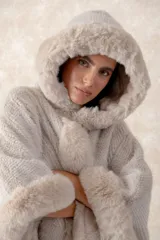 Capa de piel sintética en color negro, con diseño holgado, capucha integrada y bordes con textura de pelo largo.