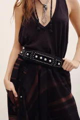 Cinturón tipo faja de cuero negro con tachas plateadas metálicas y tiras colgantes con borlas en los extremos.