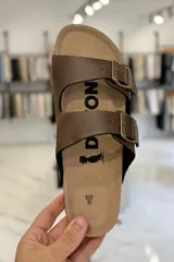Sandalia marrón con diseño de dos tiras ajustables con hebillas metálicas y plantilla anatómica.
