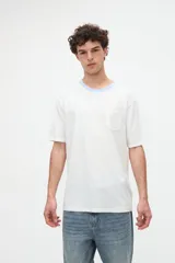 Remera blanca de algodón con textura suave, corte relaxed, manga corta, cuello redondo en contraste de color celeste y un bolsillo aplicado en el pecho.